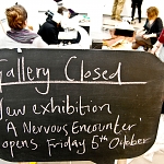 A blackboard announces the installation for 'A Nervous Encounter' begins